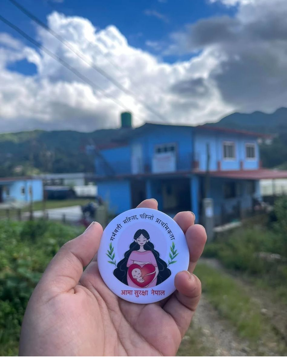 A woman holds the Aama Surakshya Nepal maternal identification badge outside a health post